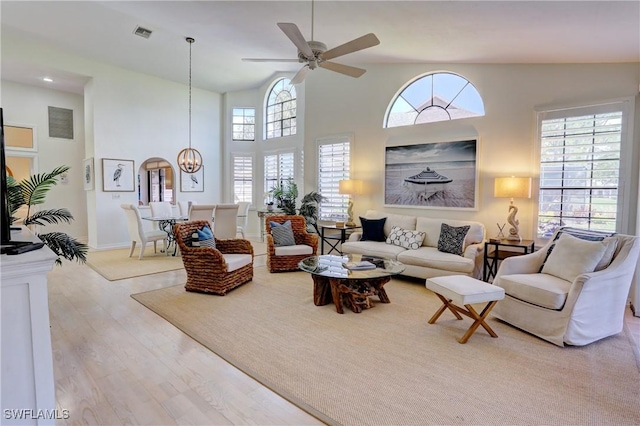 living area with plenty of natural light, ceiling fan with notable chandelier, wood finished floors, and visible vents