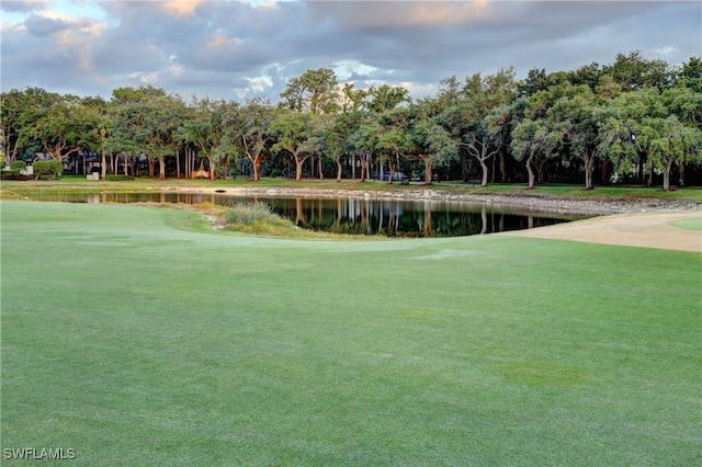 view of home's community with a yard, a water view, and view of golf course