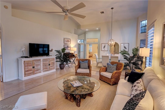 living area with high vaulted ceiling, ceiling fan, baseboards, and visible vents