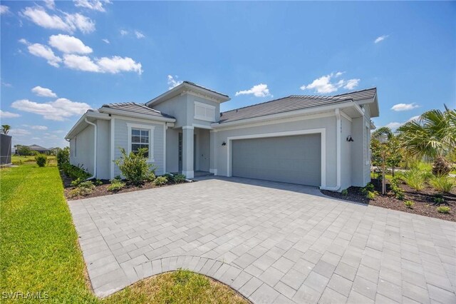 view of front of home with a garage, a front lawn, decorative driveway, stucco siding, and a tile roof