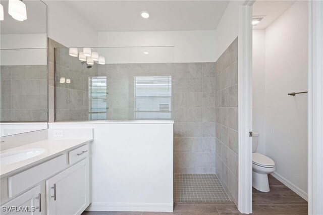 bathroom with a walk in shower, vanity, toilet, recessed lighting, and wood finished floors
