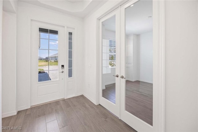 doorway featuring french doors, baseboards, and wood finished floors