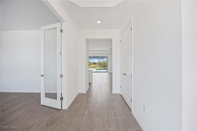 hallway featuring baseboards, recessed lighting, and wood finished floors