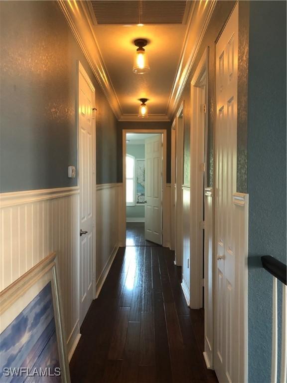 3402 Tigris Ln, Naples, FL 34119 - corridor featuring a wainscoted wall, visible vents, a textured wall, ornamental molding, and dark wood finished floors