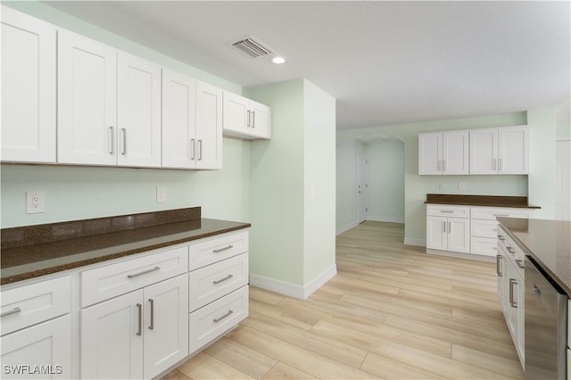 kitchen with baseboards, recessed lighting, arched walkways, white cabinetry, and visible vents