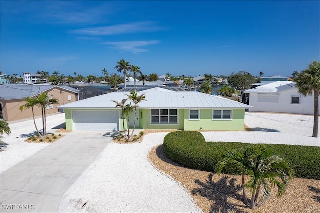ranch-style house featuring a garage, stucco siding, metal roof, and concrete driveway