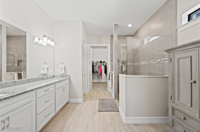 11498 Tiverton Trce, Fort Myers, FL 33913 - bathroom featuring tiled shower, double vanity, a spacious closet, and baseboards