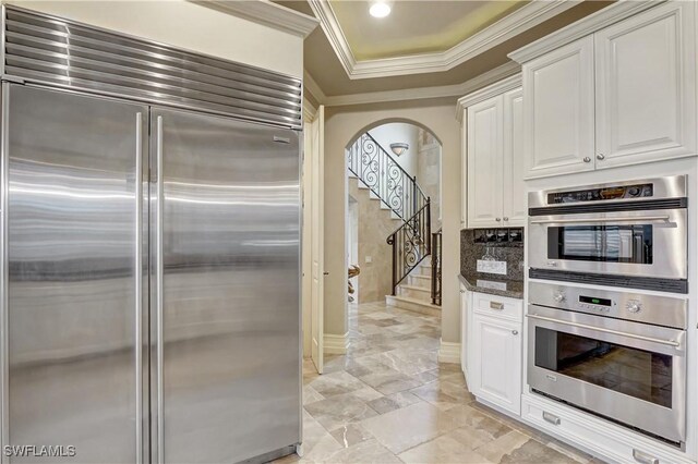 1947 Gordon River Ln, Naples, FL 34104 - kitchen with ornamental molding, white cabinets, arched walkways, dark stone countertops, and appliances with stainless steel finishes