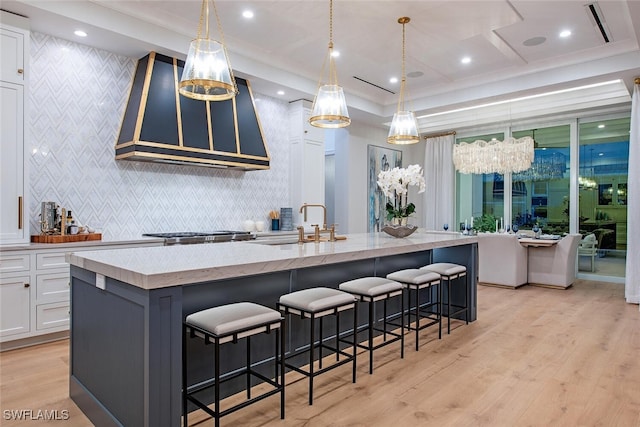 1380 Pelican Ave, Naples, FL 34102 - kitchen featuring white cabinetry, a sink, a spacious island, light stone countertops, and wall chimney exhaust hood