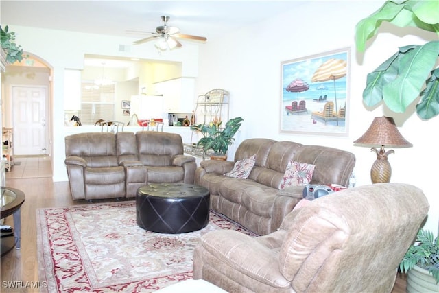 living area featuring wood finished floors and ceiling fan with notable chandelier