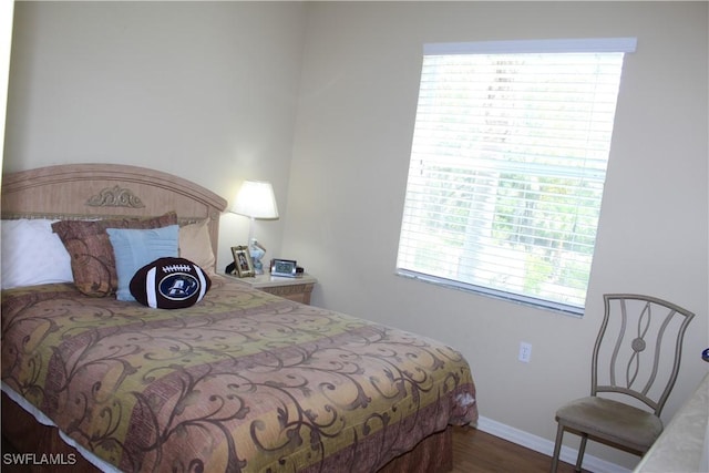 bedroom featuring multiple windows, wood finished floors, and baseboards