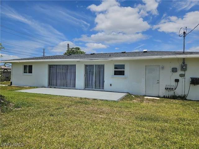 back of property with a patio, stucco siding, and a yard