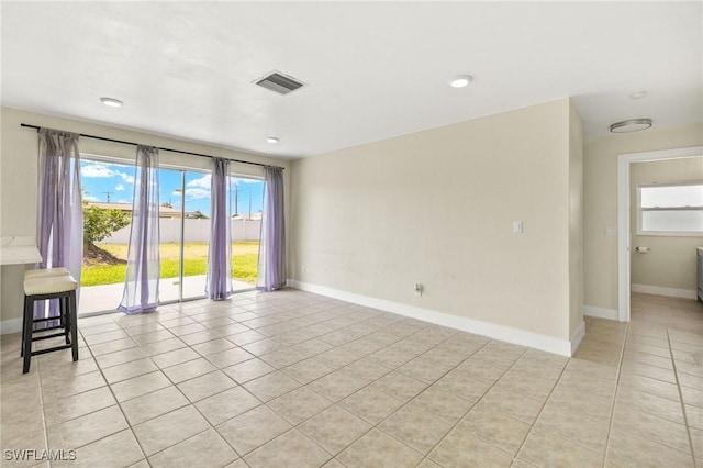 spare room featuring visible vents, light tile patterned floors, and a healthy amount of sunlight
