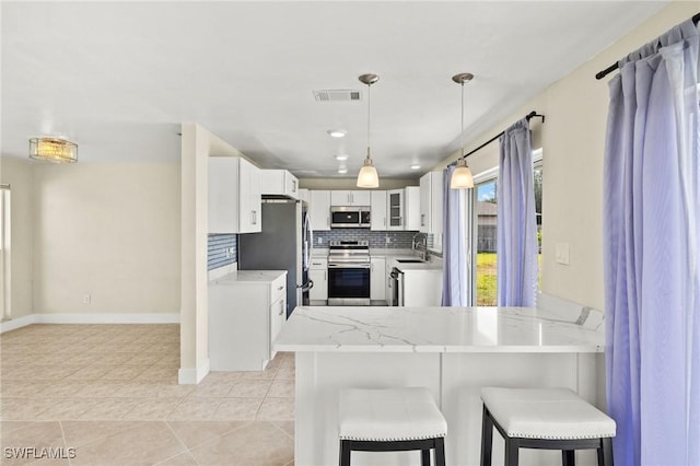 kitchen featuring white cabinets, appliances with stainless steel finishes, a sink, a peninsula, and visible vents