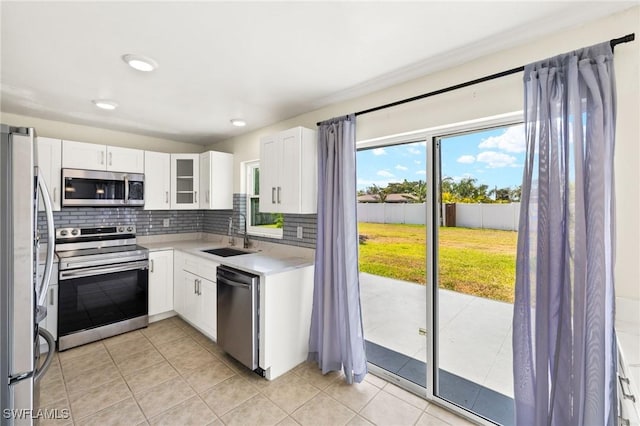 kitchen with decorative backsplash, light countertops, white cabinetry, a sink, and appliances with stainless steel finishes