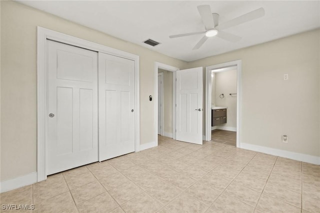 unfurnished bedroom featuring a closet, visible vents, baseboards, light tile patterned floors, and ensuite bath