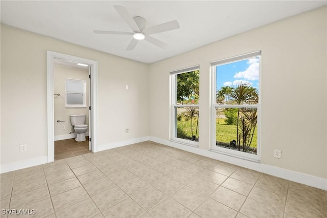 unfurnished bedroom with connected bathroom, baseboards, ceiling fan, and light tile patterned floors