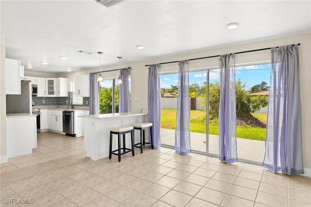 kitchen featuring visible vents, a breakfast bar, light countertops, tasteful backsplash, and stainless steel appliances