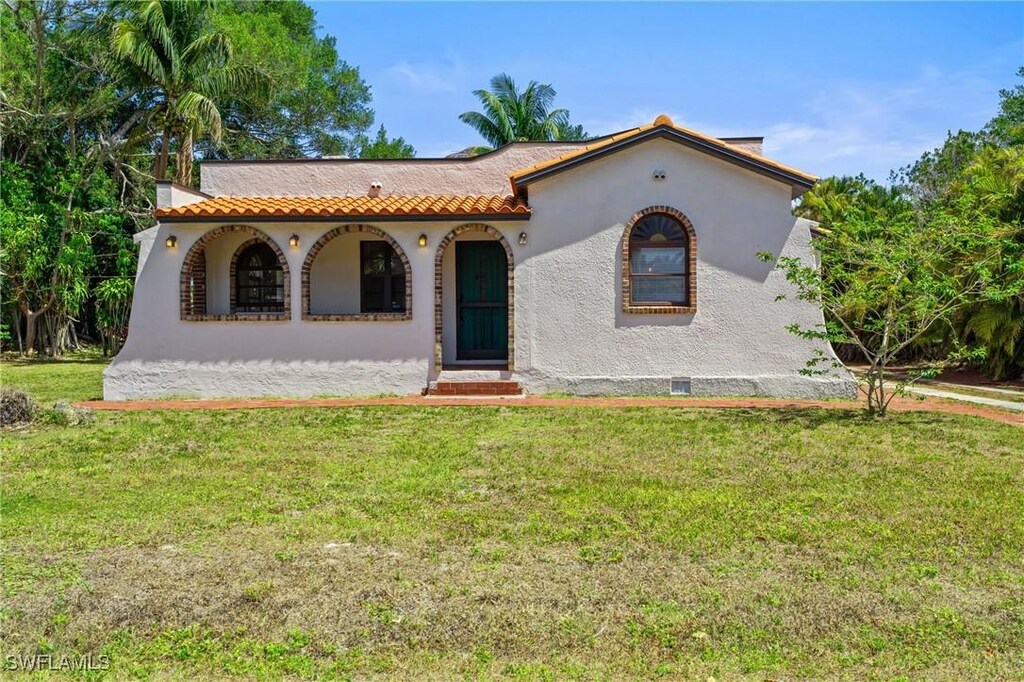 1725 Coronado Rd, Fort Myers, FL 33901 - mediterranean / spanish house featuring stucco siding, a porch, and a front lawn