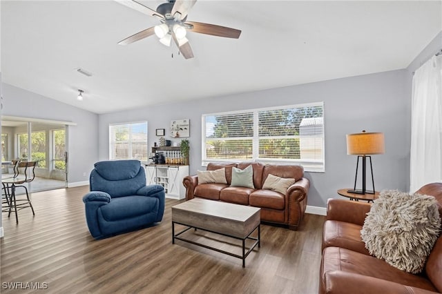 living area with ceiling fan, visible vents, baseboards, wood finished floors, and vaulted ceiling