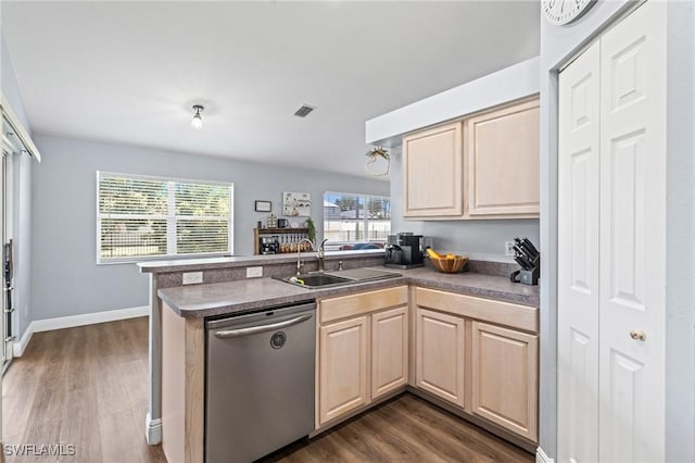 kitchen featuring light brown cabinetry, dark wood finished floors, dishwasher, a sink, and a peninsula