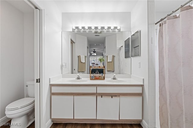 bathroom with double vanity, a sink, ceiling fan, and toilet