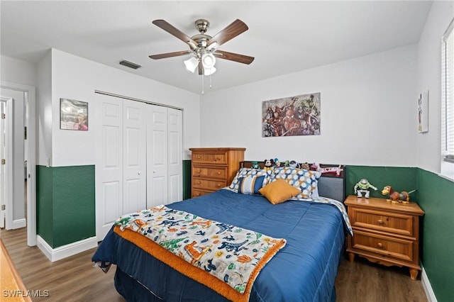 bedroom featuring a ceiling fan, baseboards, wood finished floors, visible vents, and a closet