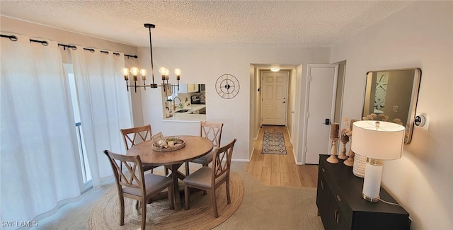dining space with a textured ceiling, a chandelier, and light colored carpet