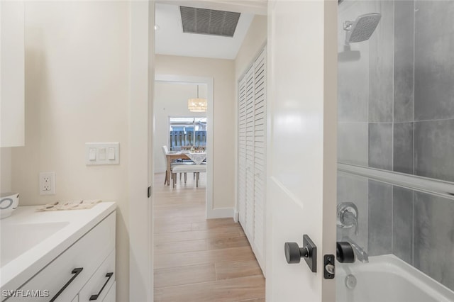 bathroom with bathing tub / shower combination, vanity, wood finished floors, and visible vents