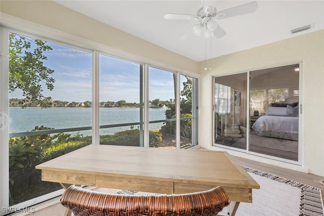 sunroom featuring visible vents, a water view, wood finished floors, and a healthy amount of sunlight