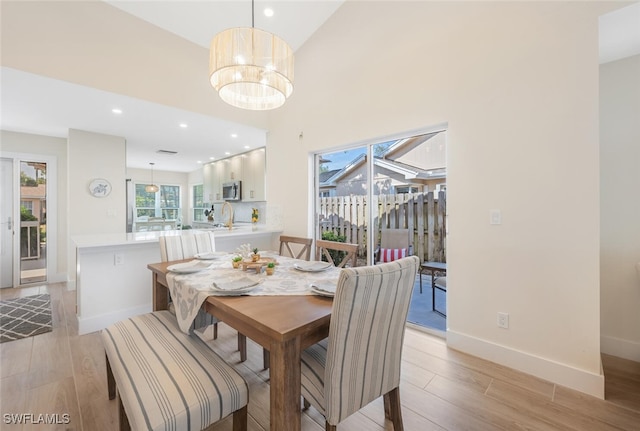 dining area featuring baseboards, recessed lighting, light wood-style flooring, and a notable chandelier