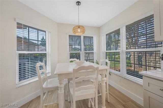 dining room with baseboards, light wood-type flooring, and an inviting chandelier