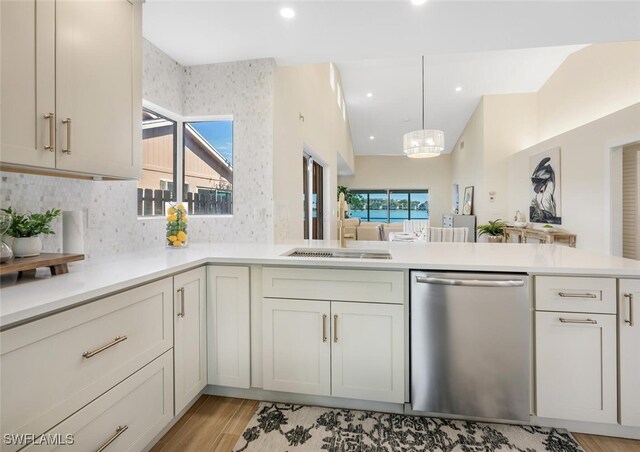 kitchen featuring decorative backsplash, dishwasher, light countertops, an inviting chandelier, and light wood-style flooring