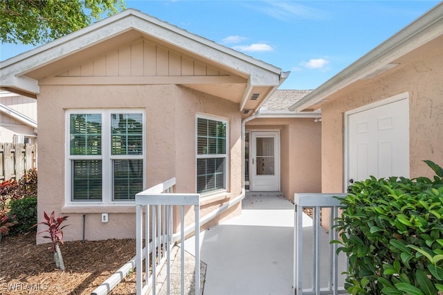 entrance to property with fence and stucco siding