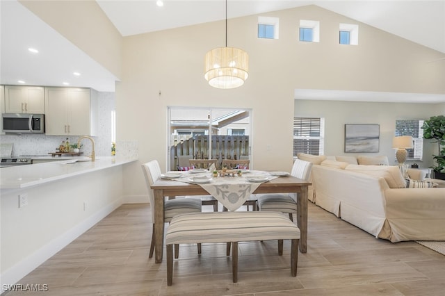 dining room with high vaulted ceiling, a chandelier, plenty of natural light, and light wood-type flooring