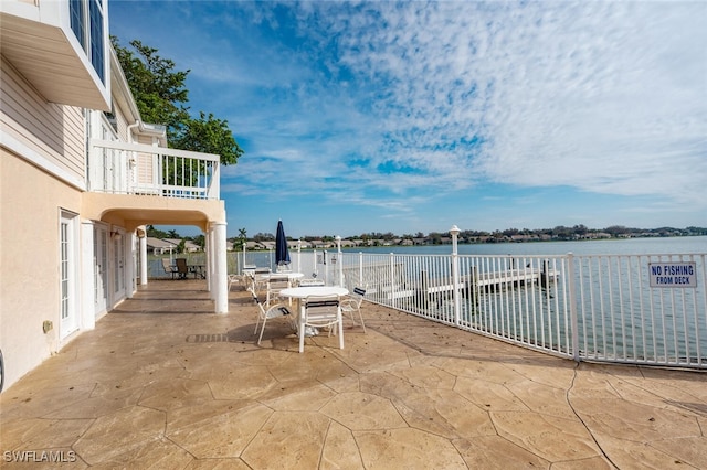 view of patio with outdoor dining space, a water view, and a balcony