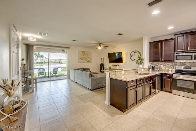 kitchen with visible vents, light tile patterned flooring, dark brown cabinets, a sink, and stainless steel appliances