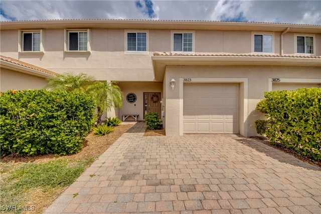 multi unit property with decorative driveway, an attached garage, and stucco siding