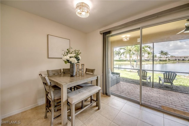 dining space with baseboards, a ceiling fan, a water view, and tile patterned floors