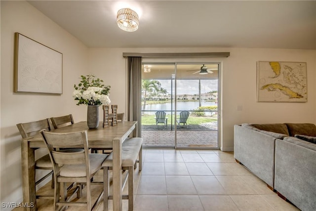 dining space with a water view, light tile patterned flooring, and ceiling fan