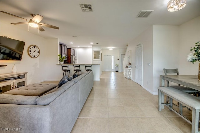 living area with visible vents, baseboards, ceiling fan, and light tile patterned floors