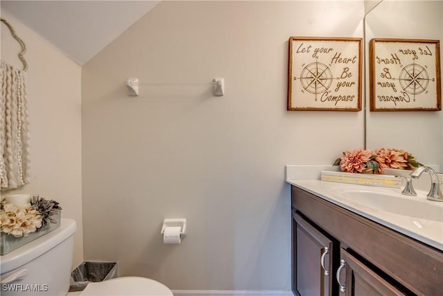 bathroom with vanity, lofted ceiling, and toilet