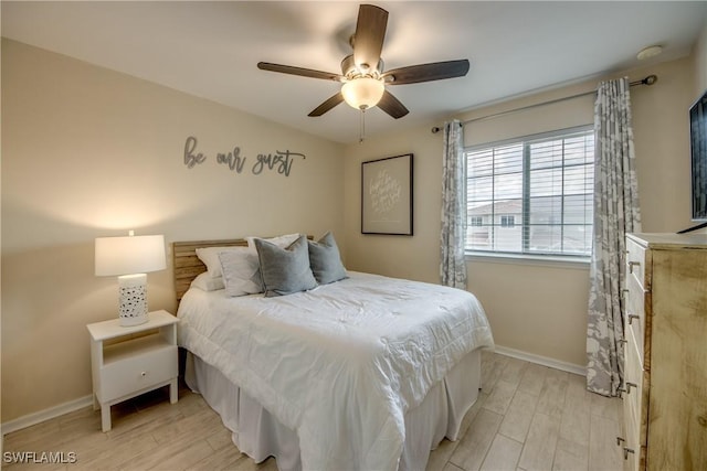 bedroom with light wood-style floors, baseboards, and ceiling fan