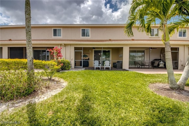 rear view of house with a lawn, a ceiling fan, a patio area, and stucco siding
