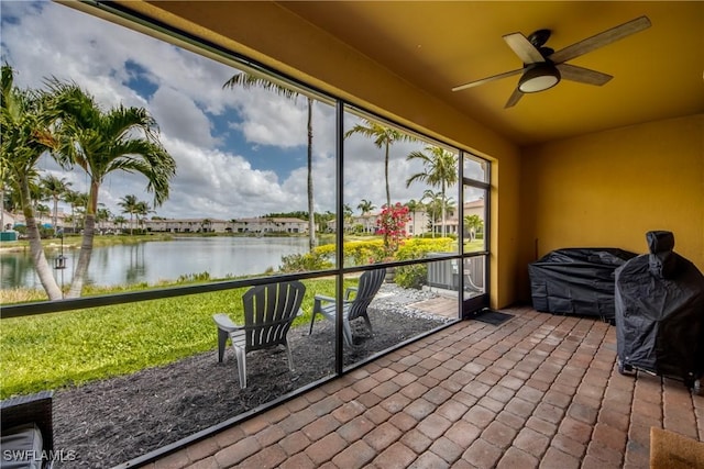sunroom featuring a water view and ceiling fan