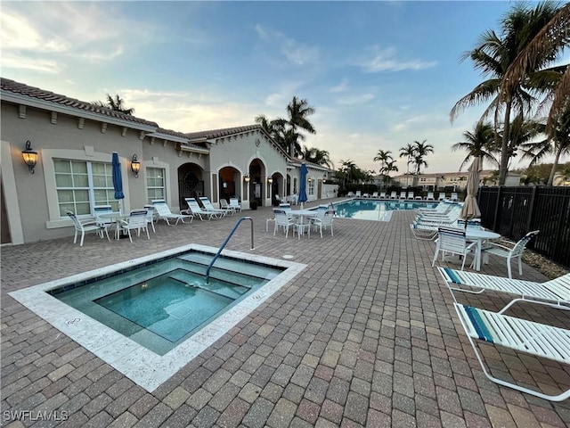 community pool with a patio, fence, outdoor dining area, and a community hot tub