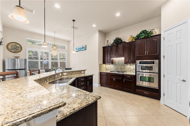kitchen featuring decorative backsplash, decorative light fixtures, light tile patterned floors, appliances with stainless steel finishes, and a sink