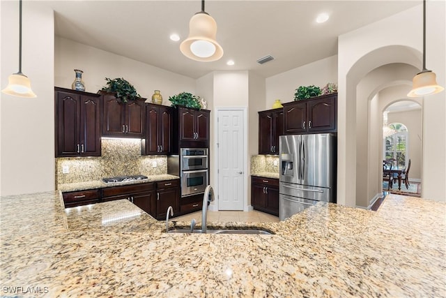 kitchen with appliances with stainless steel finishes, dark brown cabinets, backsplash, a sink, and visible vents