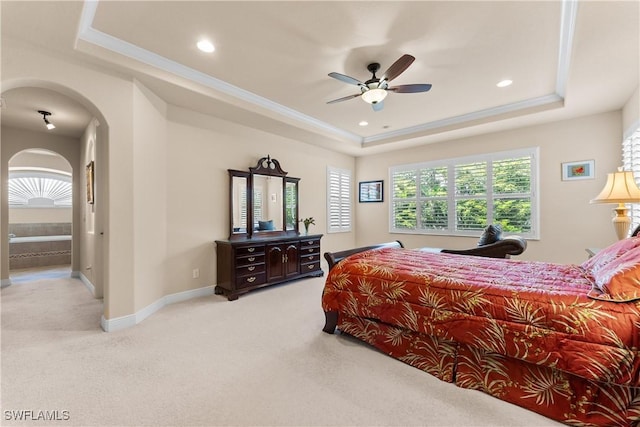 bedroom featuring recessed lighting, arched walkways, light carpet, and a tray ceiling