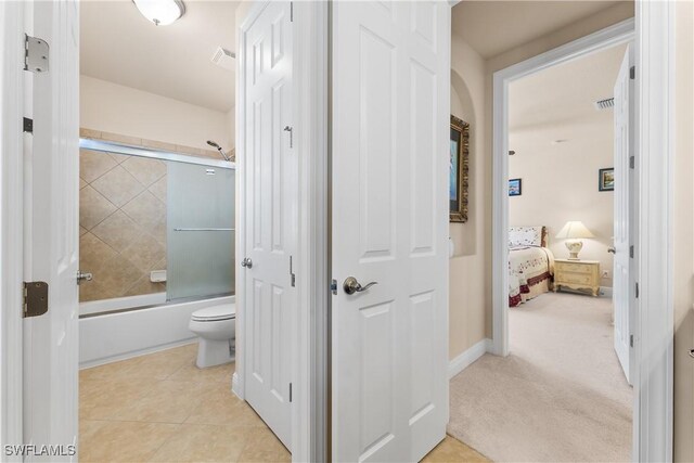 full bath with toilet, bath / shower combo with glass door, and tile patterned floors